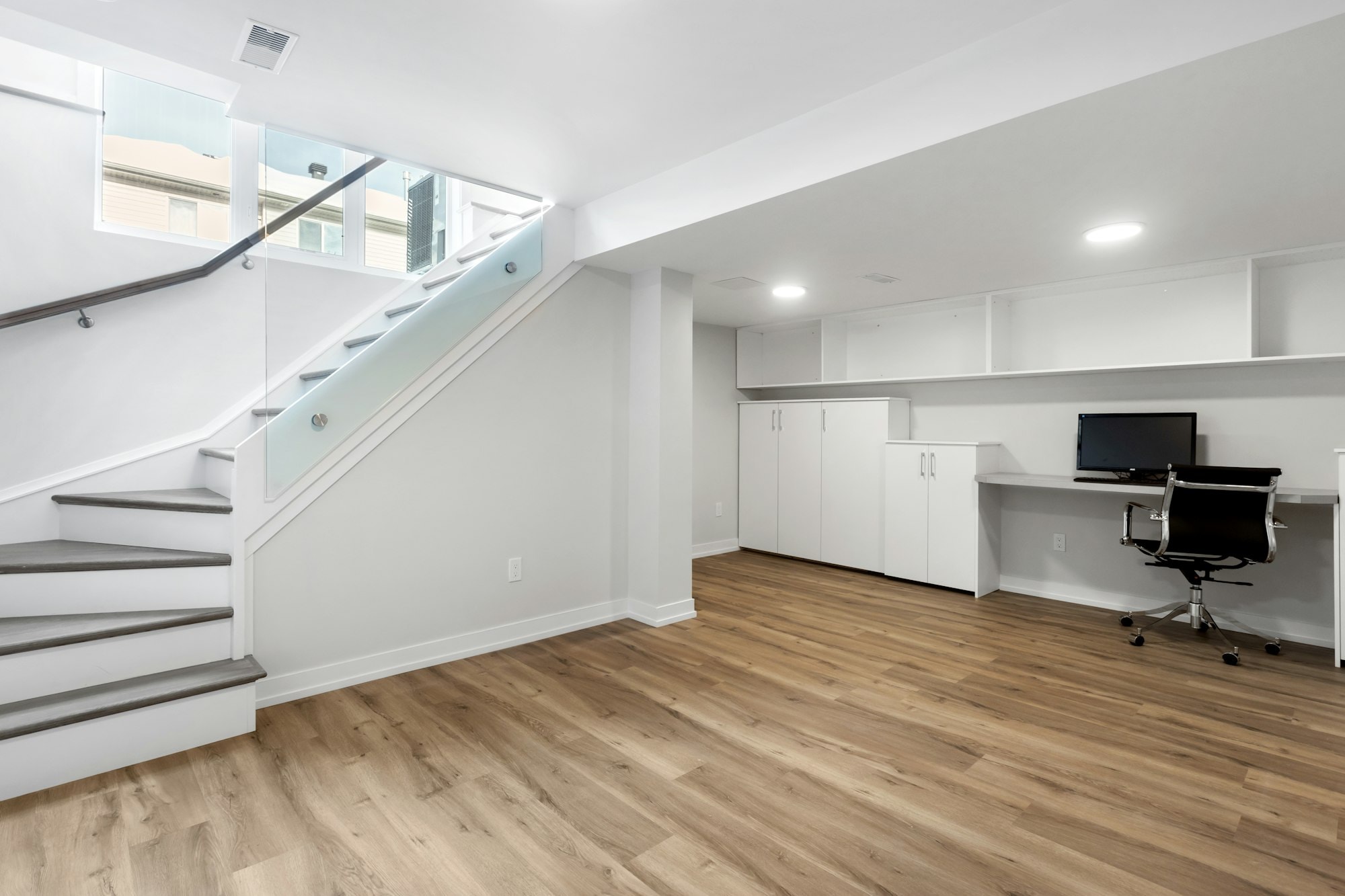 Finished basement suite with a glass-railed stair and pot lights